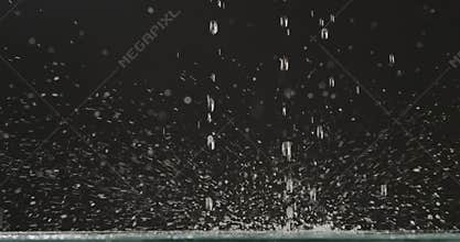 Running water falls from above with splashes and droplets of water, scattering in different directions against a black
