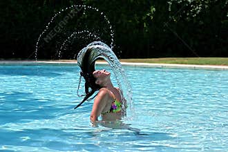 Girl or woman in swimming pool throwing wet hair back