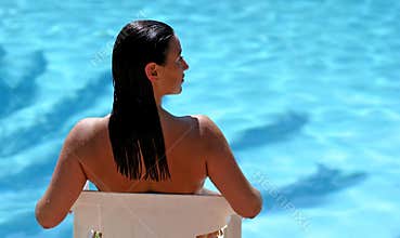 Attractive woman by blue sunny swimming pool