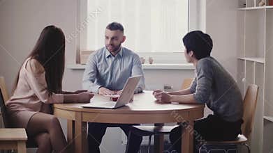 Beautiful woman boss listening to young Japanese man at job interview in modern office, Caucasian employee joins in.
