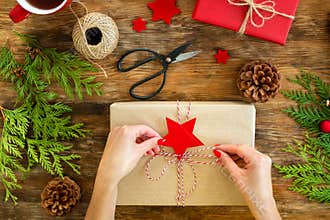 DIY Gift Wrapping. Woman wrapping beautiful red christmas gifts on rustic wooden table. Overhead view christmas wrapping.