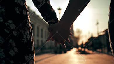 Couple hands holding each other on city street sunset light with beautiful lens flare