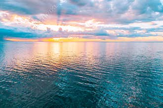 Sun, clouds, and calm water surface.