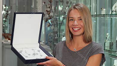 Gorgeous happy woman smiling to the camera holding expensive jewelry set
