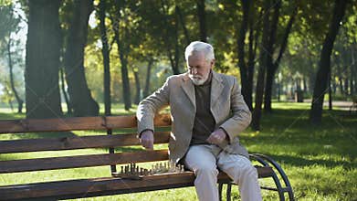 Confident elderly man playing chess and relaxing in park, happy life in old age