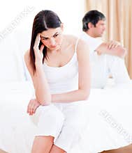 Upset couple having an argument sitting on bed