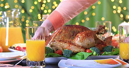 Hands putting roasted turkey on festive table closeup