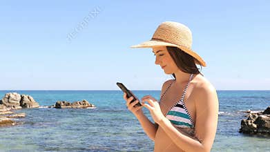 Amazed tourist in bikini checking phone on vacation