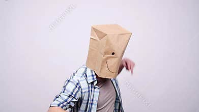 Happy man in a paper bag dancing on a gray background