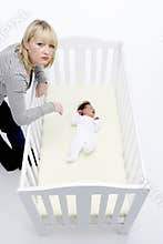 Stressed Mother Looking At Baby In Cot