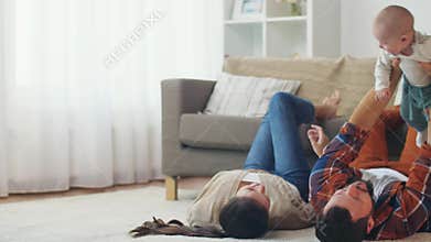 Happy mother and father playing with baby at home