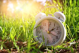 Image of spring Time Change. Summer back concept. Vintage alarm Clock outdoors.