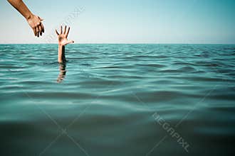 Help hand for drowning man life saving in sea or ocean.