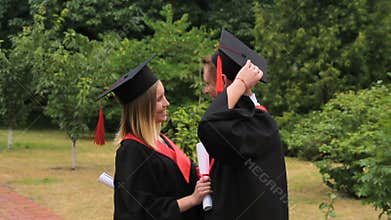Glad woman and man in academic dresses embracing after graduation ceremony