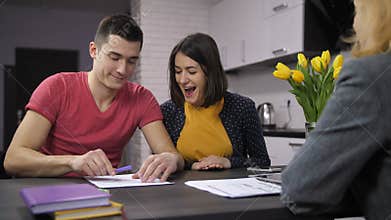 Cheerful couple signing contract with estate agent