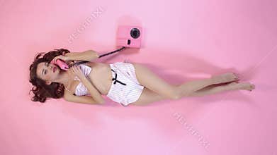 Young woman studio isolated on pink in pajamas top view holding handset talking with boyfriend