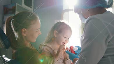 Young woman, her daughter and dentist in a dental office, a stomatologist telling how to care for teeth
