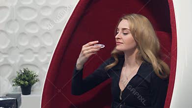 Young blond girl inserts whitening trays in the mouth before the procedure of teeth whitening.