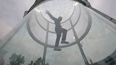 Man skydiver flies in wind tunnel. Indoor skydiving wind tunnel