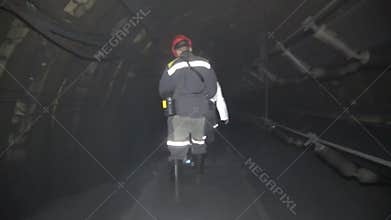Miners walking along a tunnel in a coal mine
