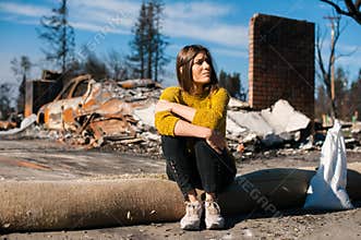 Woman at burned ruined house and yard, after fire disaster