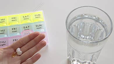 Woman takes pills from pill box and drink water. Healthcare and medicine