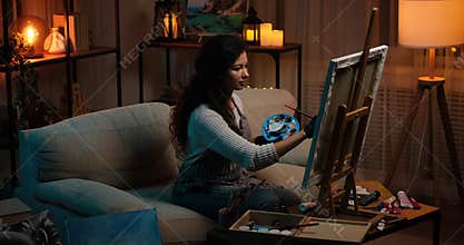 Woman painting using watercolor paint on canvas