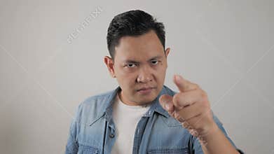 Portrait of Asian man showing cynical unhappy angry facial expression pointing forward, giving warn