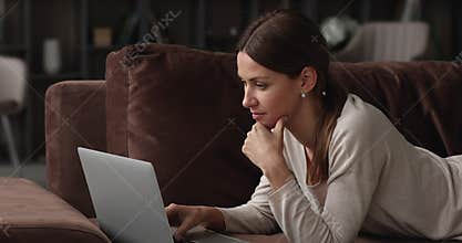 Dreamy young caucasian woman using laptop application.