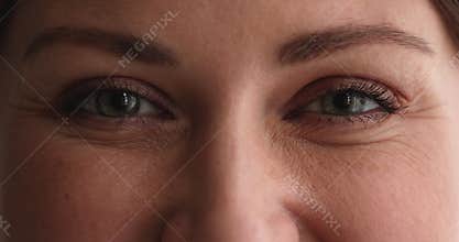 Close up young woman with green eyes looking at camera.