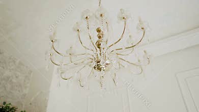 Retro chandelier hanging in san room, beautiful gold lamp of vintage style. Crystal details decorating chandelier