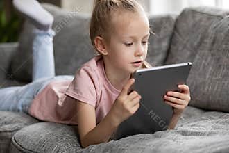 Focused cute preschooler girl watching movie, animated films