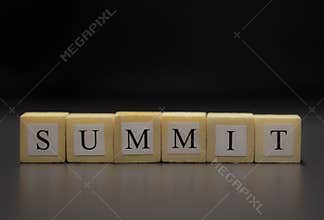 The word SUMMIT written on wooden cubes isolated on a black background