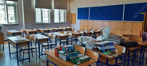 typical empty public high school classroom with wooden desks and education materials put on desks for educating students children