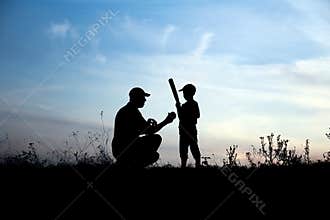 Silhouette of father and son playing baseball on nature family sport