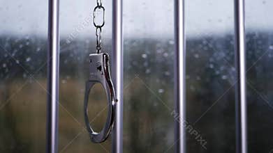 Handcuffs swing on prison bars
