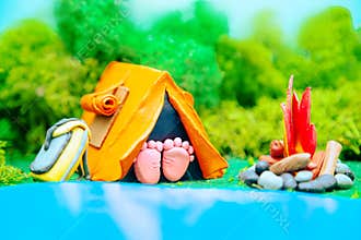 Plasticine landscape with a tent, a campfire and a backpack in the middle of the forest