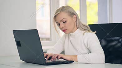 Focused young caucasian woman college university student doing homework assignment using laptop computer typing studying
