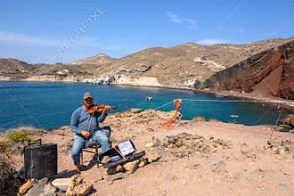 Greek music artist on the shore of the Red Beach on Santorini Island. Cyclady, Greece