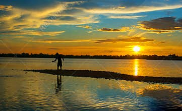 Silhouette of Thai Fisherman catching the fish in twilight  Beautiful Sunset in the sky with sky blue and orange light of the sun