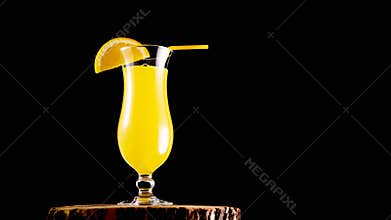 Alcoholic cocktail with a straw on a black background. Yellow lemonade in a glass on a wooden board. Fruit drink