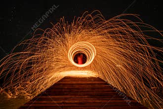 Fire dancing show swing lighting effects circle on bridge dark sky on night time.