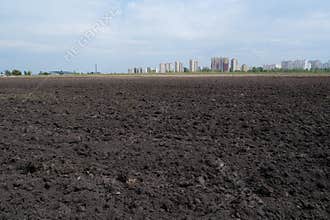 A plowed black soil field near city