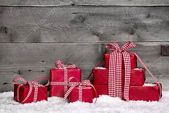 Stack of red Christmas gifts,snow on grey wooden background.