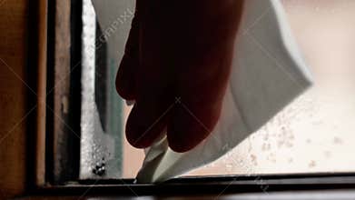 Wiping wet window glass with drops and black mould defect.