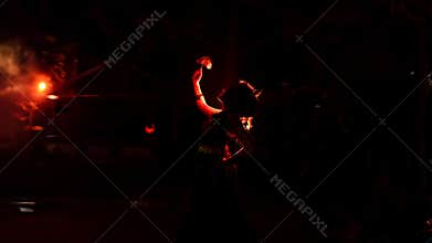 the silhouette of a female dancer holding jewelry shines brightly around the flames and looks bold in the dark