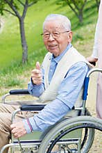Asian senior man sitting on a wheelchair with thumb up