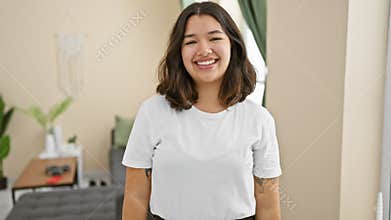 Lucky young hispanic woman radiates pure joy, standing inside home flashing a cool, confident smile full of happiness