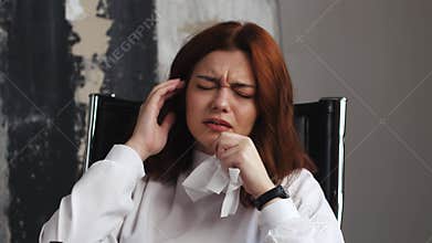 Cough, sneezing, runny nose. Business woman sitting at workplace works at laptop coughs and wipes her nose with napkin