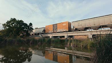 Freight train on bridge over creek at sunset